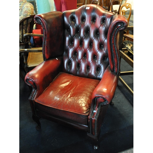 521 - Reproduction red leather finish button backed fireside wing easy chair on cabriole legs. 
(B.P. 21% ... 