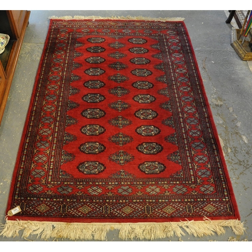 543 - Middle Eastern design red ground carpet with central field of stylised guls and geometric decoration... 