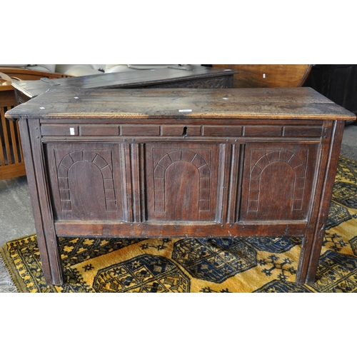 562 - 18th Century oak coffer, the moulded hinged top above three fielded panels with arched carved decora... 