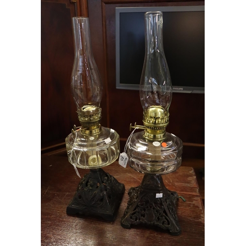 80 - Two similar early 20th century double oil burners with clear glass reservoirs, standing on pierced c... 