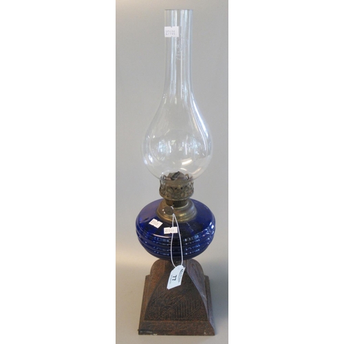 77 - Brass single burner oil lamp with coloured glass reservoir on cast metal base with clear chimney, ov... 