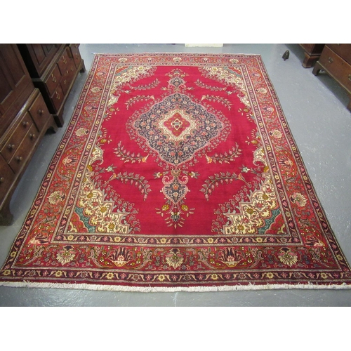 518 - Middle Eastern design Tabriz carpet on a red ground, the borders with multi-coloured geometric flora... 