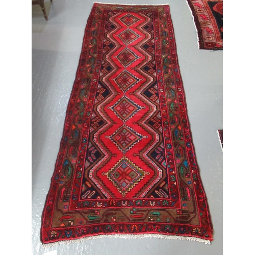 521 - Middle Eastern design Hamadan runner on a red ground with central lozenge medallions decorated with ... 