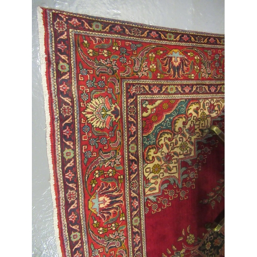 689 - Middle Eastern design Tabriz carpet on a red ground, the borders with multi-coloured geometric flora... 