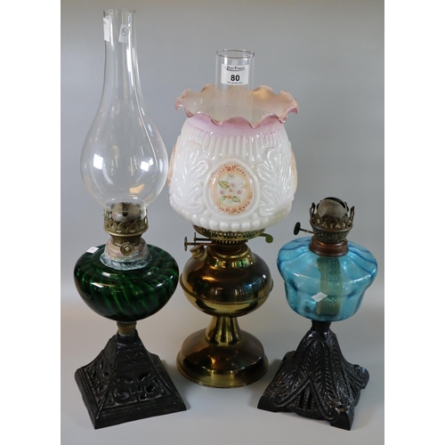 80 - Two early 20th century single  burner oil lamps with coloured reservoirs, on cast metal bases. Toget... 