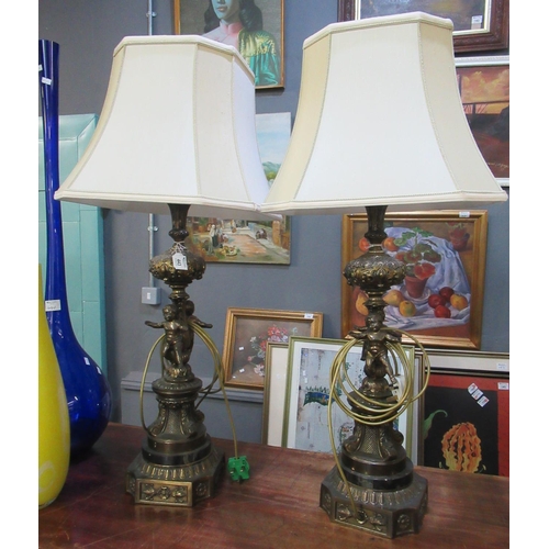 443 - Pair of modern gilded cast metal and marble table lamps with shades, modelled as cherubs on a scroll... 