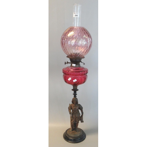 344 - Early 20th century double oil burner lamp, having cranberry globular shade above a cranberry reservo... 