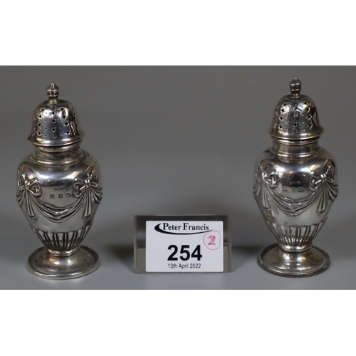 254 - Pair of late Victorian silver pepperettes with ribbon and swag designs. Birmingham 1899. 2.5oz troy ... 