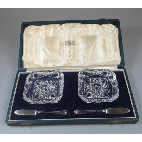 336 - Cased set of two glass square butter dishes with two silver butter knives, the box labeled Harrods, ... 
