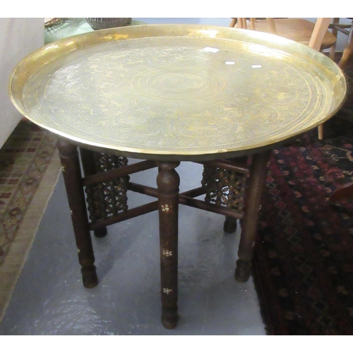 550 - Middle Eastern design brass tray top folding table on a carved hard wood base.
(B.P. 21% + VAT)