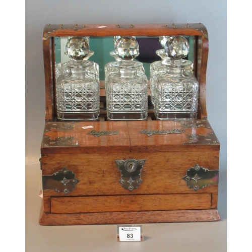 83 - Early 20th century oak metal mounted three bottle tantalus having lidded compartments for cigars and... 