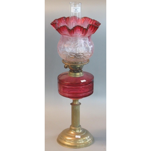 83 - Early 20th century double oil burner lamp having cranberry and clear glass shade above a cranberry g... 