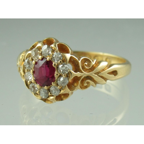 220 - A Victorian oval ruby and diamond cluster ring in 18ct gold mount with engraved shoulders.  Ring siz... 