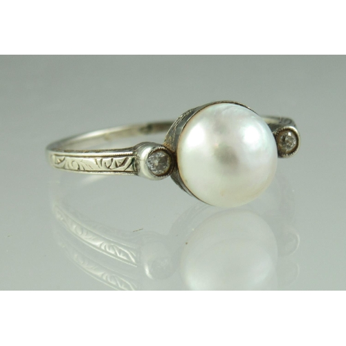 232 - An early 20th century pearl and diamond ring set in engraved white metal with an engraved band.  Rin... 