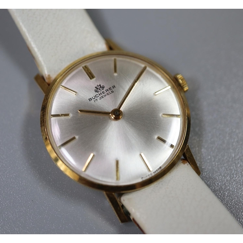 275 - 18ct gold Bucherer ladies mechanical wrist watch, having satin face with baton numerals on white lea... 