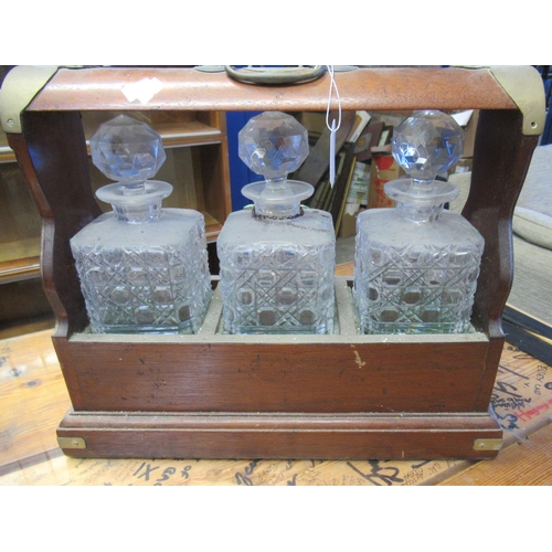 551 - Victorian style mahogany and brass banded three section tantalus with glass decanters and a plated w... 