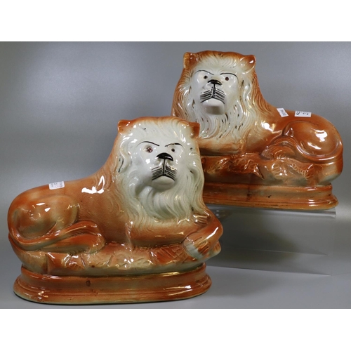 213 - Pair of early 20th century Staffordshire fireside recumbent lions with painted features (missing the... 