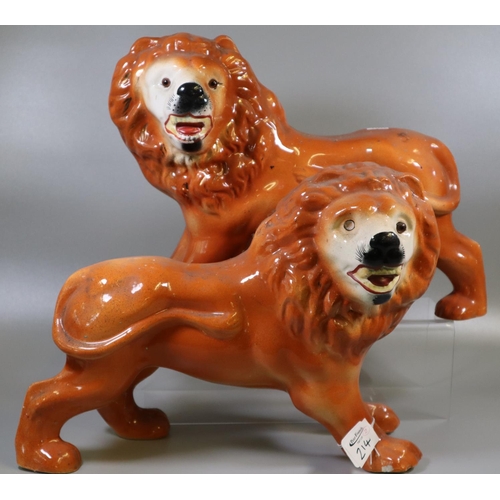 214 - Pair of early 20th century Staffordshire pottery fireside standing lions with painted features and g... 