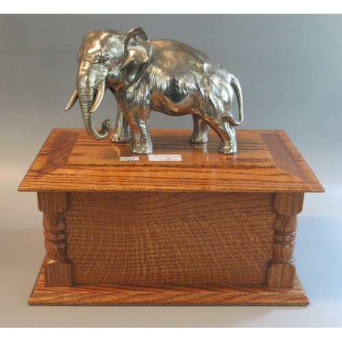 70 - Silver plated sculpture of an African elephant mounted on a tall oak box shaped plinth.  33cm across... 