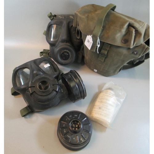 86 - Two vintage military gas masks, one contained in a military canvas satchel. 
(B.P. 21% + VAT)