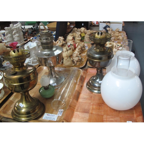 376 - Two trays with three brass and white metal oil lamps, with three glass chimneys and two opaline glas... 