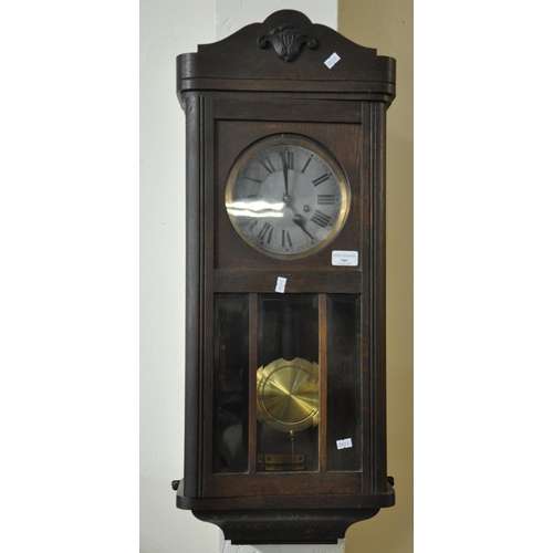 509 - Mid century oak two train wall clock with brass pendulum and key.  (B.P. 21% + VAT)