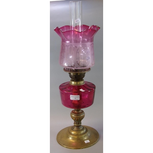 75 - Early 20th Century double oil burner lamp, having frosted cranberry glass shade, above a cranberry g... 