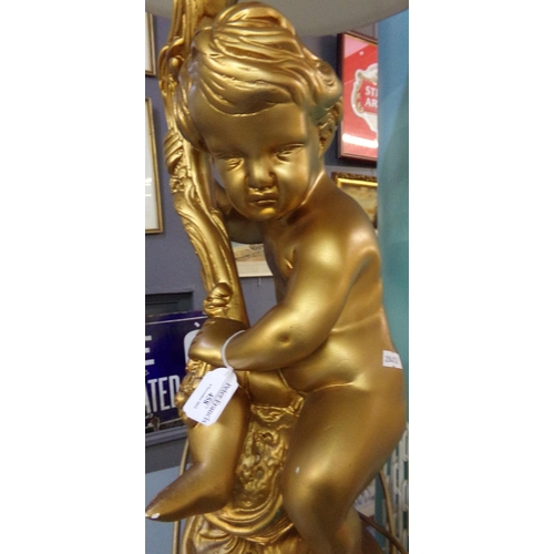 458 - Modern gilded finish table lamp in the form of a seated cherub on scroll decorated base, with shade.... 