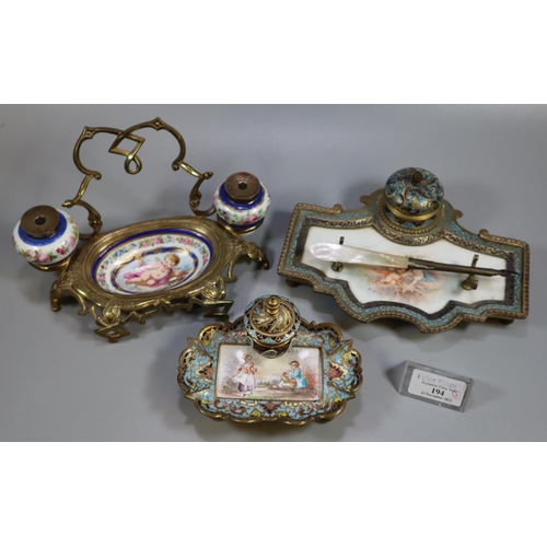 194 - Two similar champleve enamel and gilt metal single desk inkwells, both having porcelain panels of fi... 