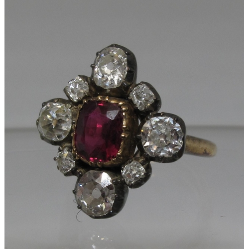 311 - Victorian ruby and diamond ring. The ruby set in silver and surrounded by old cut diamonds on a late...