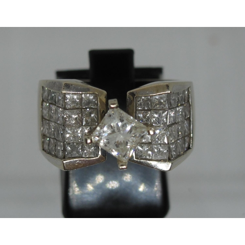 359 - 14ct white gold diamond ring set in Modernist style.  The central princess cut diamond flanked by pa... 