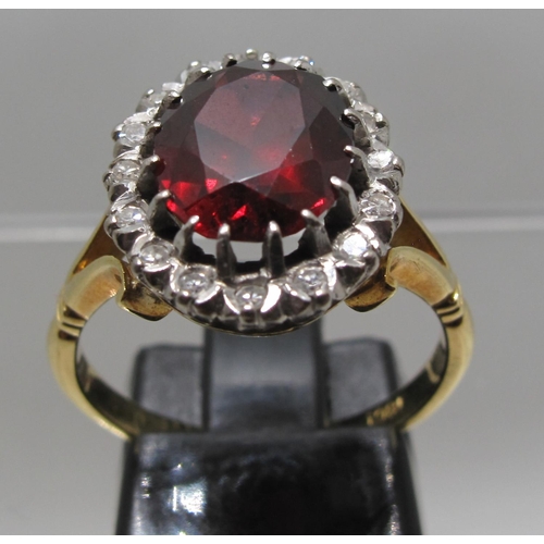 371 - 18ct gold ring set with a large oval red stone surrounded by diamonds.  Ring size N.  Approx weight ... 