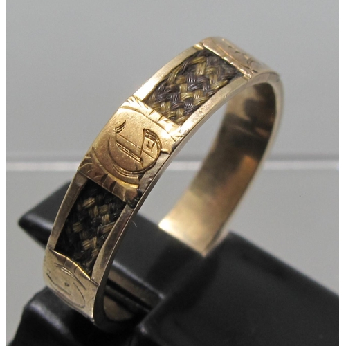 379 - A Victorian mourning ring with six panels of plaited hair separated by gold panels each engraved wit... 