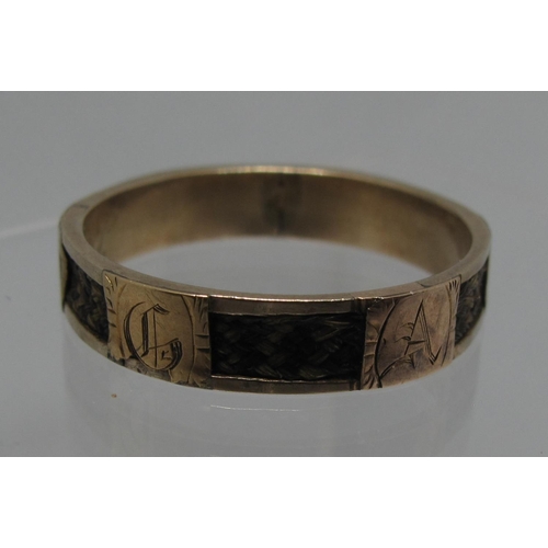 379 - A Victorian mourning ring with six panels of plaited hair separated by gold panels each engraved wit... 