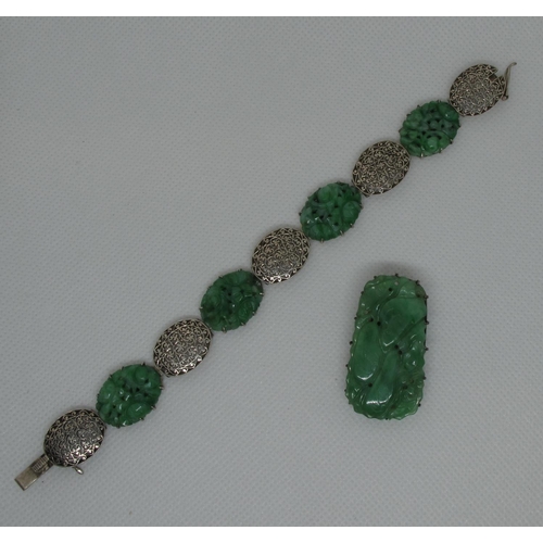 385 - A green leather cantilever jewellery box containing an Art Deco jade carved dress clip and a carved ... 