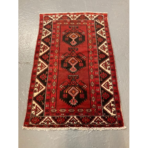 436 - Red ground Baluchi Nomadic rug, having three central stylised floral medallions with decoration of f... 