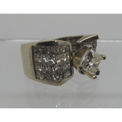 359 - 14ct white gold diamond ring set in Modernist style.  The central princess cut diamond flanked by pa... 