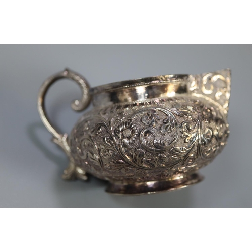 239 - White metal probably Indian baluster single handled cream jug with repoussé floral and foliate decor... 