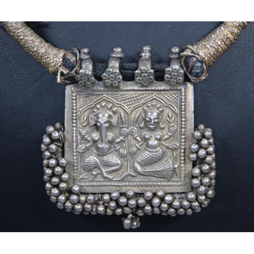 432 - Unusual Indian design white metal pendant with relief cast gods, on cord necklet.  (B.P. 21% + VAT)