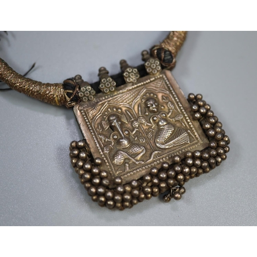 432 - Unusual Indian design white metal pendant with relief cast gods, on cord necklet.  (B.P. 21% + VAT)