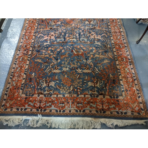 714 - Chinese Persian style blue ground rug, overall decorated with animals, birds and hunting scenes, wit... 