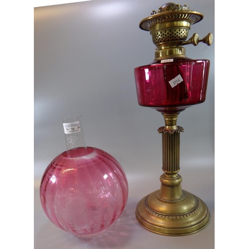 79 - Early 20th Century double oil burner lamp, having cranberry glass etched globular shade, above a cra... 