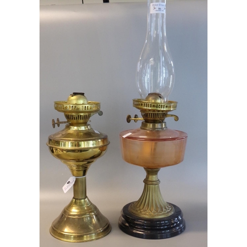 86 - Early 20th Century double oil burner lamp, having orange reservoir on a brass and ebonised base. Tog... 