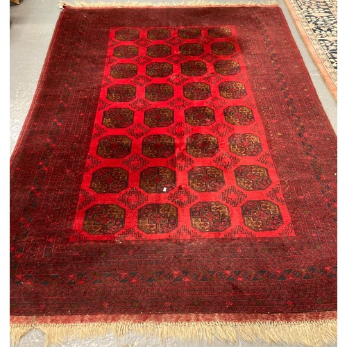 646 - Middle Eastern design red ground carpet with a collection of central geometric medallions flanked by... 