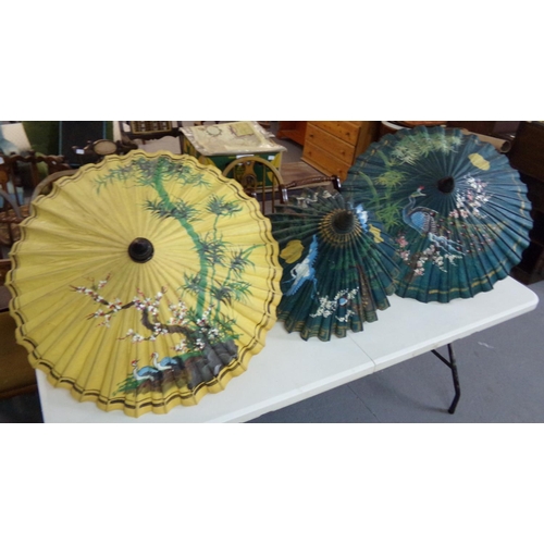 395 - Three oriental painted parasols with exotic birds, flowers, trees etc design and turned wooden handl... 