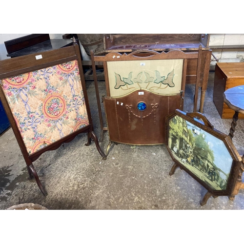 551 - Group of four fire screens, one copper and brass with ceramic panel, two with embroidered banners, t... 