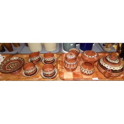 365 - Two trays of slipware pottery items, to include: teapot, cups and saucers, lidded jug, pedestal dish... 