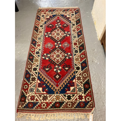 595 - Hand woven probably Turkish red ground runner decorated with stylised flowerheads and two taratalu m... 