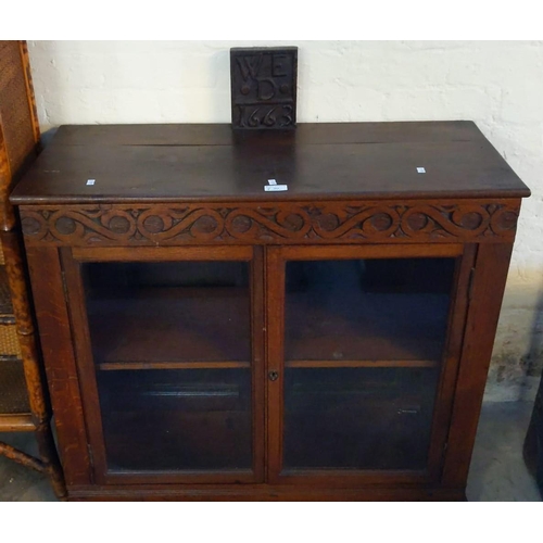 562 - Carved oak low cabinet with two glazed doors and strap work frieze bearing date panel 1663 (a recons... 