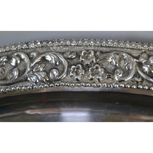 262 - Silver Indian shallow tray of oval form, overall decorated with flowerheads, scroll work and foliage... 